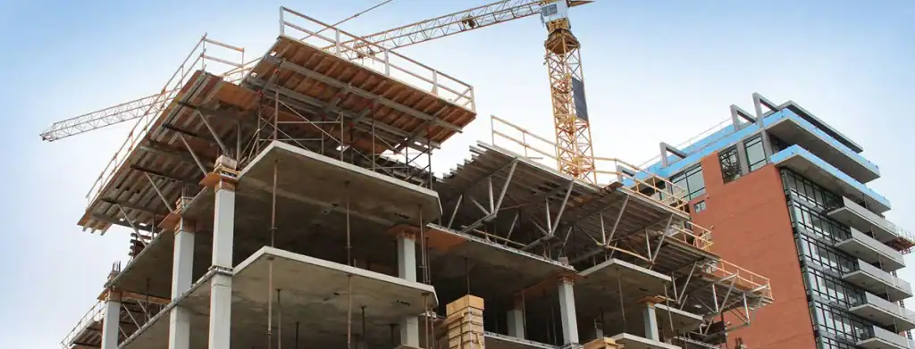 A building under construction features cranes, scaffolding, and electrical contractors New Hampshire on site.